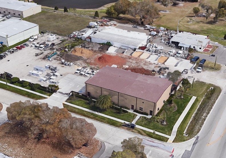 Aerial view of a brown metal building on a lot with landscaping supplies.